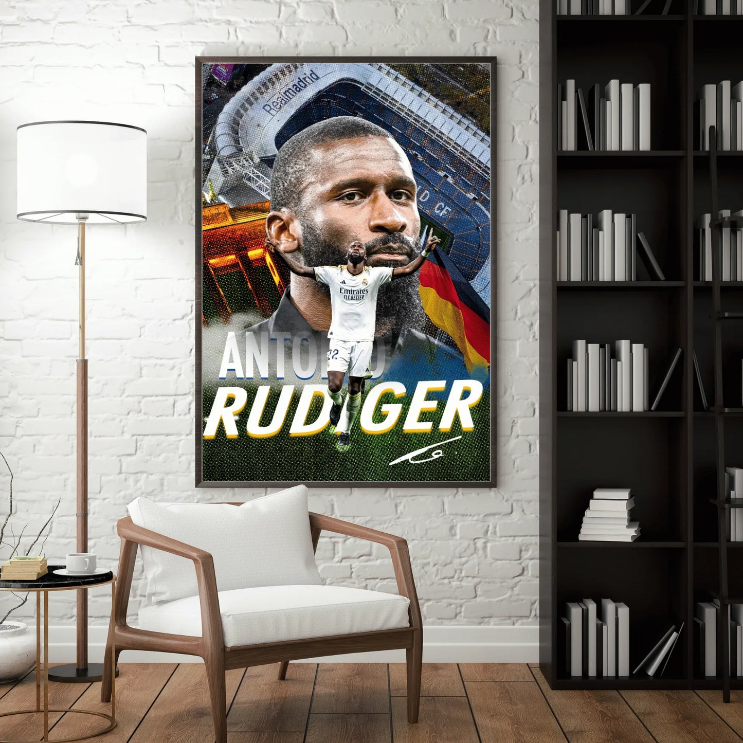 Interior mockup of a framed Antonio Rüdiger poster displayed on a white brick wall beside a wooden chair and bookshelf.
