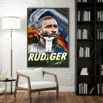 Interior mockup of a framed Antonio Rüdiger poster displayed on a white brick wall beside a wooden chair and bookshelf.